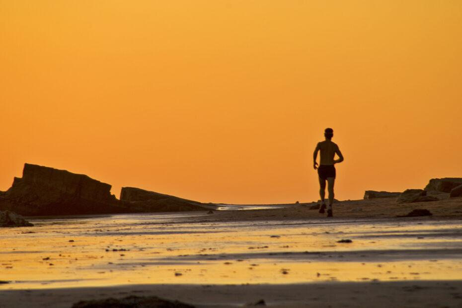 Corredor solitário na praia treinando sua velocidade e estimulando o VO2 max