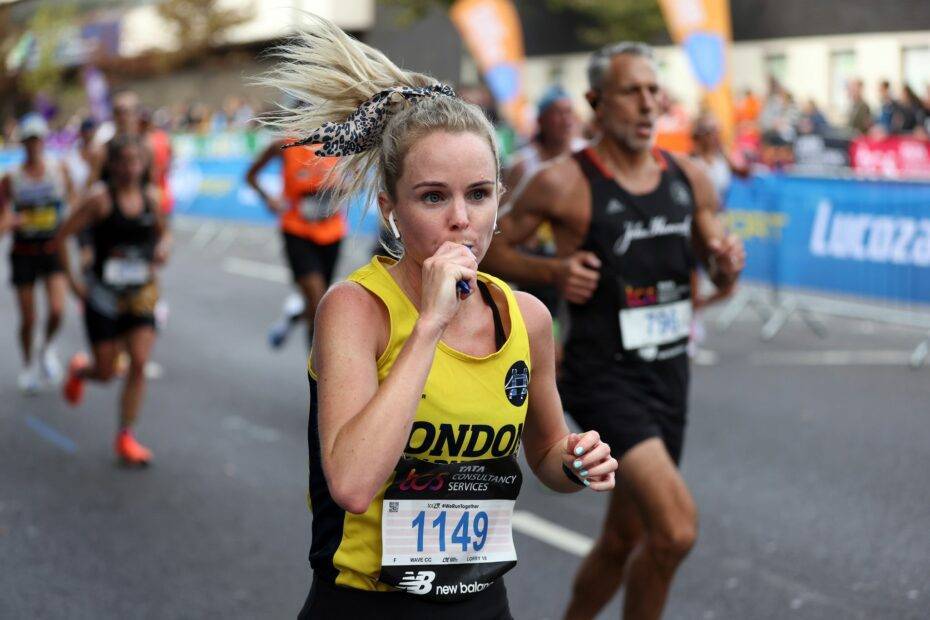 Corredora na maratona de Londres consumindo carboidrato intra-treino para manter o seu bom desempenho