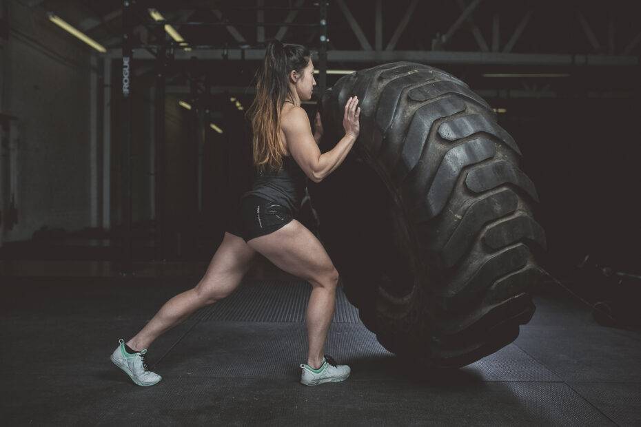 Mulher na academia executando um TireFlip após incorporar estratégias de retorno aos treinos