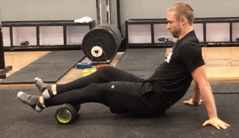 Pessoa vestida de preto, fazendo o uso do foam rolling na panturrilha